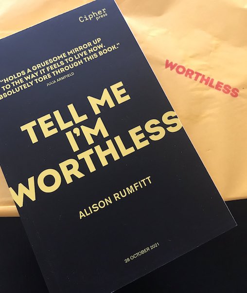Proof copy of Tell Me I'm Worthless with yellow text on a black background and yellow tissue paper with a red stamp saying 'worthless'.