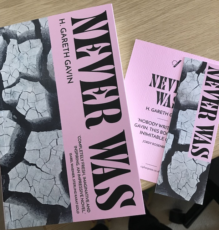 The book Never Was with a matching bookmark and postcard.